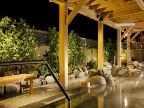 a pavilion with a bench and rocks in a yard at Air Terminal Hotel in Chitose