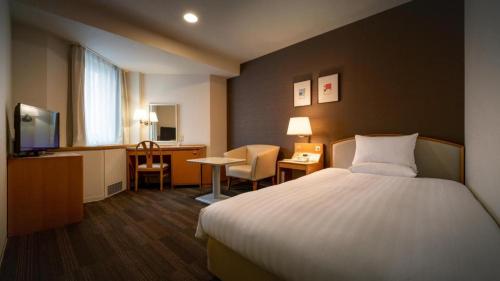 a hotel room with a bed and a desk at Air Terminal Hotel in Chitose