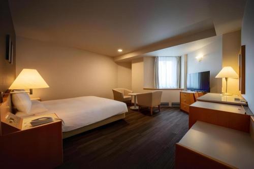 a hotel room with a bed and a table and chairs at Air Terminal Hotel in Chitose