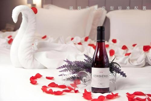 a bottle of wine sitting on a bed with red roses at Lavande Hotels Suzhou Railway Station in Suzhou