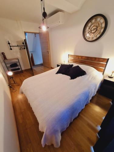 a bedroom with a white bed and a clock on the wall at La maison de Roméo in Pont-d'Ouilly