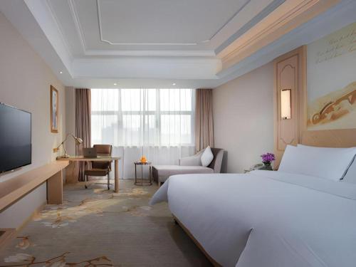 una camera d'albergo con un letto, una scrivania e una televisione di Vienna International Hotel Wuxi Taihu Expo Center a Wuxi