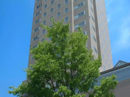 a tree in front of a tall building at Grand Hotel New Oji in Tomakomai