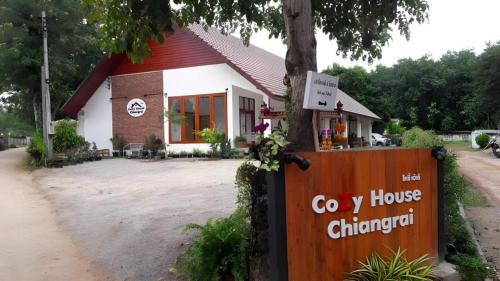 a building with a sign in front of it at CoZy House Chiangrai in Chiang Rai