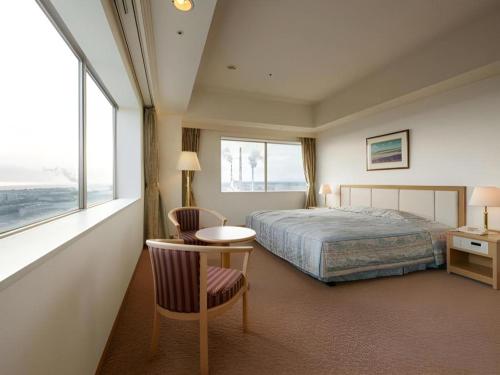 a hotel room with a bed and a table and chairs at Grand Hotel New Oji in Tomakomai