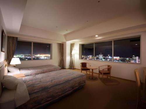 a hotel room with a bed and a table with chairs at Grand Hotel New Oji in Tomakomai