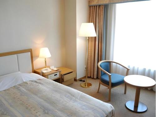 a hotel room with a bed and a chair and a desk at Grand Hotel New Oji in Tomakomai