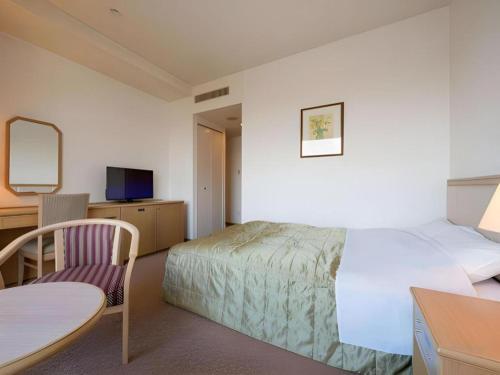 a hotel room with a bed and a table and a mirror at Grand Hotel New Oji in Tomakomai