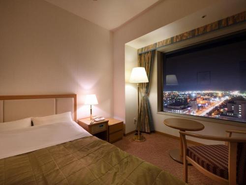 a hotel room with a bed and a large window at Grand Hotel New Oji in Tomakomai