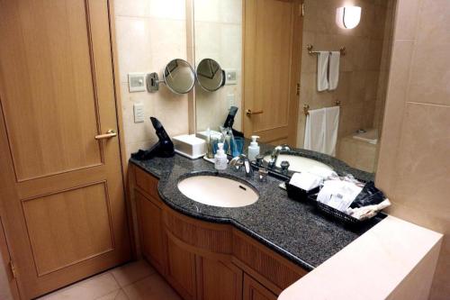 a bathroom with a sink and a mirror at Grand Hotel New Oji in Tomakomai