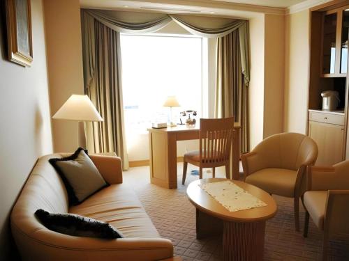 a living room with a couch and chairs and a table at Grand Hotel New Oji in Tomakomai