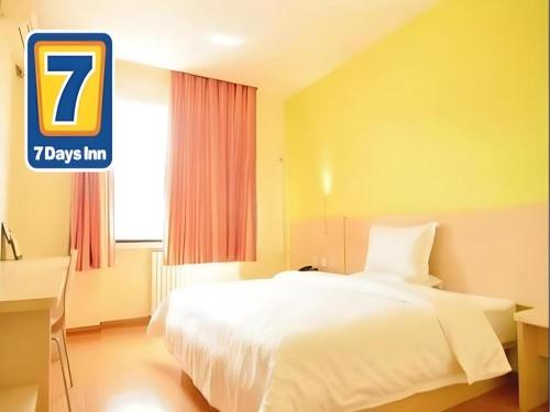 a hotel room with a white bed and a sign at 7 Days Inn Changzhou Yancheng Technology Metro Station in Changzhou