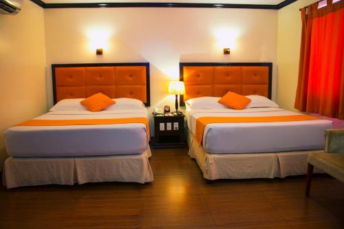 two beds in a hotel room with orange pillows at Paradise Garden Hotel and Convention Center Boracay Powered by ASTON in Boracay