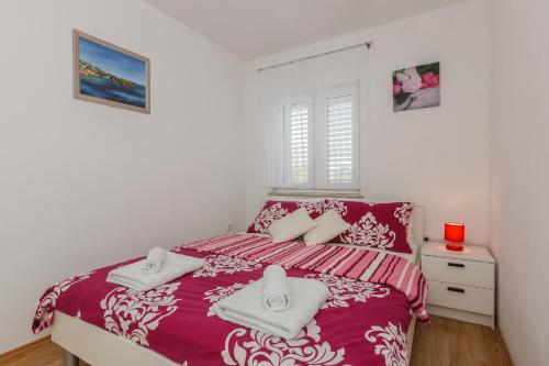 a bedroom with a red bed with towels on it at Apartment Anna in Kaštela