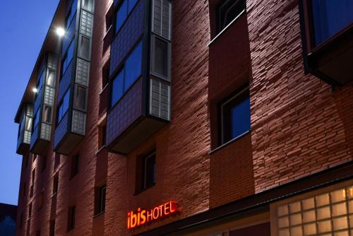 a brick building with a neon sign on it at ibis Amsterdam Centre Stopera in Amsterdam