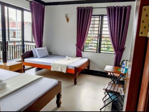 a bedroom with a bed and a window with purple curtains at Paradise Cozy Guesthouse Sihanoukville in Sihanoukville