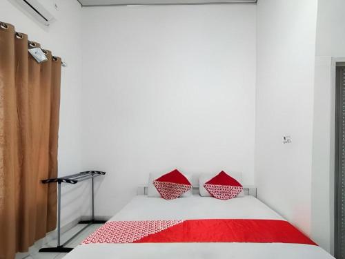 a bedroom with a bed with two red pillows at OYO 91886 Bfs Homestay Syariah in Jambi