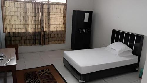 a bedroom with a bed and a desk and a window at Hotel O Jahip Syariah in Bojong Dua