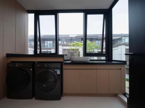 a kitchen with a washing machine and a counter with windows at Qi Yi Nanxu Pavilion Homestay in Kunming