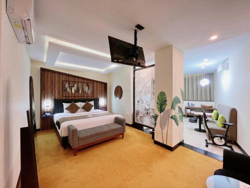 a bedroom with a large bed and a living room at Oak Tree Urban Hotel Jakarta in Jakarta