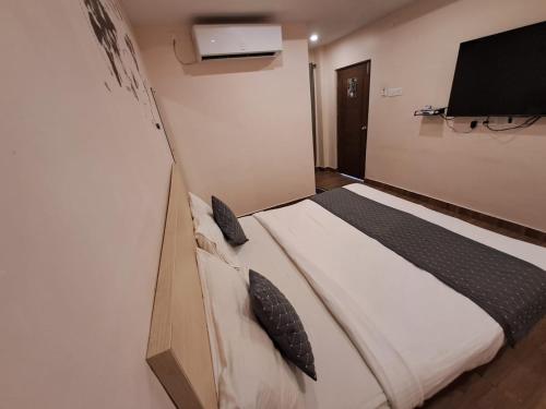 a bedroom with a bed and a flat screen tv at De Crown Luxury Hotel in Kākināda