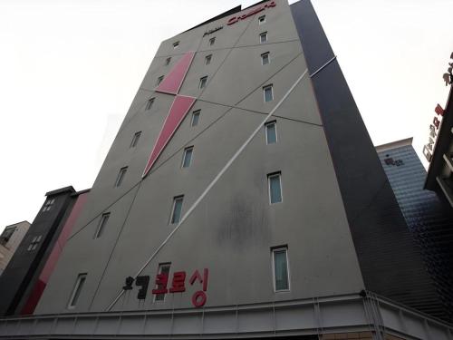 a tall gray building with a red sign on it at Crossing Hotel in Seoul