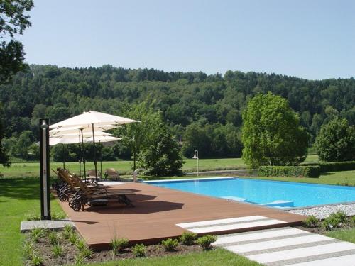 einen Pool mit Tischen, Stühlen und einem Sonnenschirm in der Unterkunft Parkhotel Bad Schandau mit SPA in Bad Schandau