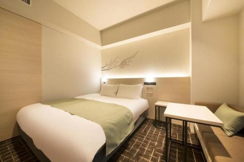 a small bedroom with a bed and a table at Hotel Yaenomidori Tokyo in Tokyo