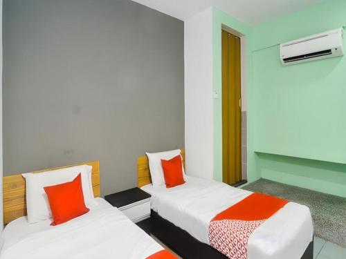 a room with two beds with orange and white pillows at OYO 89465 Golden Lounge in Kuching