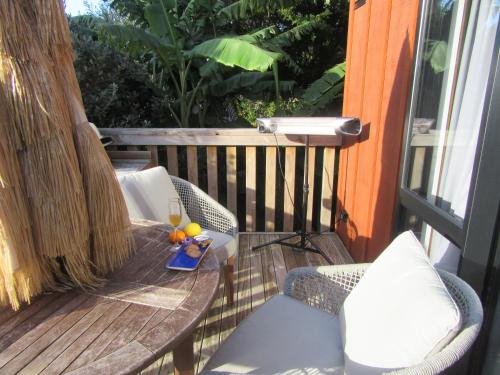 a table and chairs on a balcony with a glass of wine at Peace Of Bali in Waihi Beach