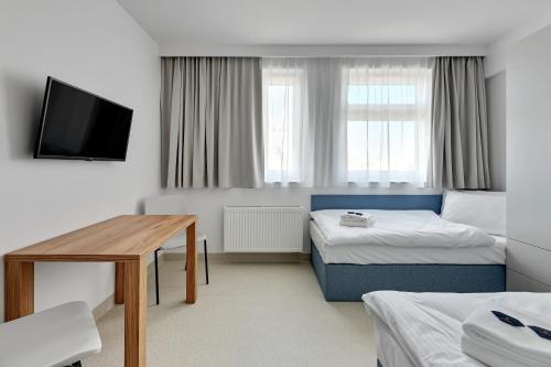 a room with two beds and a table and a tv at Apartgdynia in Gdynia