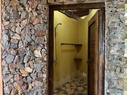 a bathroom with a stone wall and a walk in shower at LooLa Adventure Resort in Telukbakau