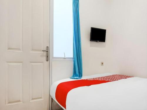 a bedroom with a bed and a window with a television at Super OYO 91074 Stariez Senen Syariah in Jakarta