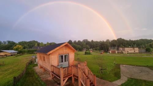 a rainbow over a wooden house in a field at Vakantiehuisje Appel & Fleur in Swalmen