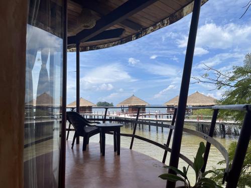 a balcony with a table and a chair and the water at LooLa Adventure Resort in Telukbakau