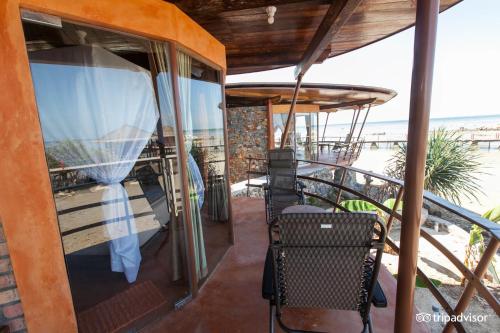a balcony with a table and chairs and the ocean at LooLa Adventure Resort in Telukbakau