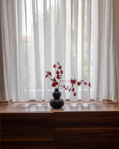a vase with flowers on a dresser in front of a window at Hotel SOLO 127 in Prizren