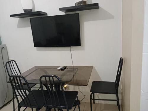 a dining room table with chairs and a television on a wall at Alyssa Sea Residence MOA condotel in Manila