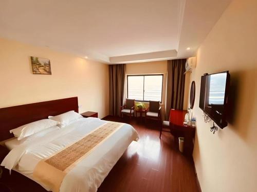 une chambre d'hôtel avec un lit et une télévision à écran plat dans l'établissement GreenTree Inn Jiangsu Huaian Bus Terminal North Station Huaihai North Road Business Hotel, à Huai'an