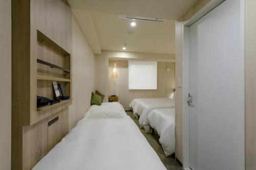 two beds in a room with white sheets at Hotel IL FIORE Kasai in Tokyo
