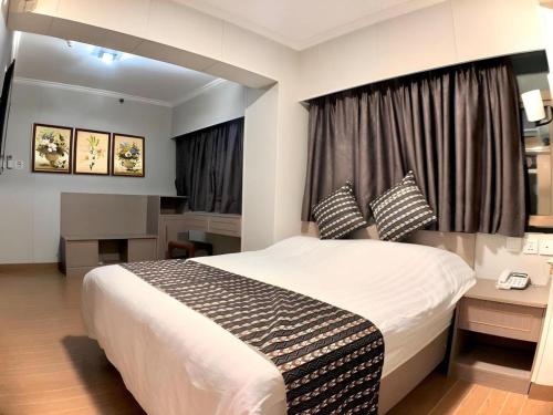 a bedroom with a bed and a desk and a window at Holiday Hotel in Macau