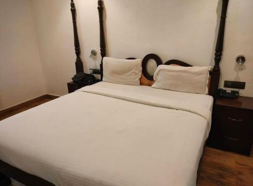 a bedroom with a large bed with white sheets and pillows at Bagah Beach Hotel in Anjuna