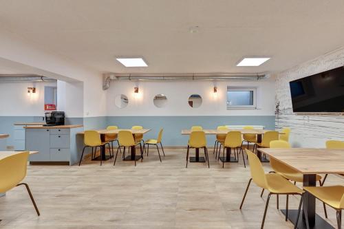 a large room with tables and yellow chairs at Apartgdynia in Gdynia