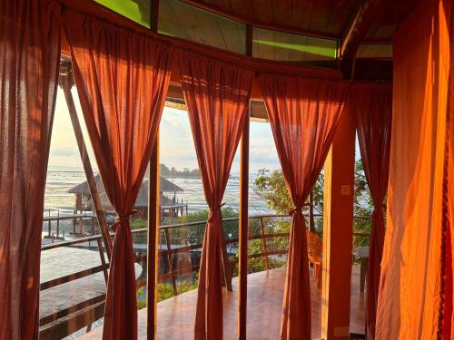 a room with a view of the ocean through the curtains at LooLa Adventure Resort in Telukbakau