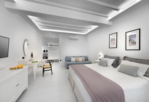 a white bedroom with a large bed and a desk at Deliades Hotel in Ornos