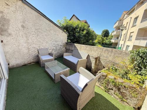 a patio with chairs and tables and a wall at Calme et confort tout équipé au cœur de Moirans in Moirans