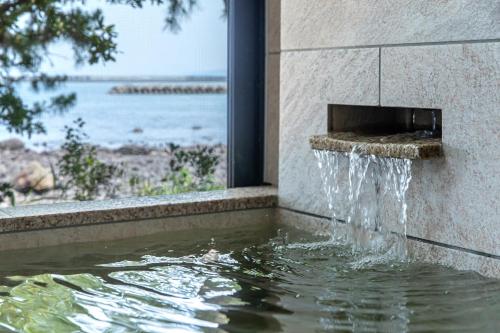 a water fountain on the side of a building at Ishinoya Beppu - TKP Hotels & Resorts in Beppu