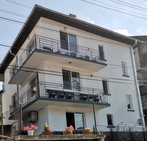a white building with balconies and potted plants at Къща за гости - Софи, гр. Девин in Devin