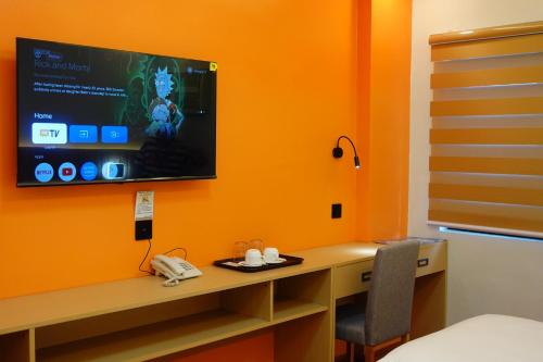 a room with a desk with a television on a wall at YMCA Makati in Manila