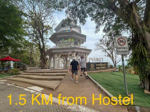 two people walking in front of a monument in a park at Comfort Hostel Phuket Old Town by MaTong in Phuket Town